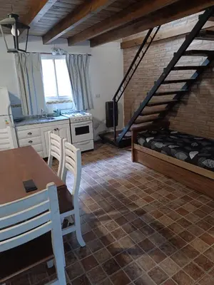 a kitchen with a table and a bed in a room at Sonidos del Rio Aparts in Santa Rosa de Calamuchita