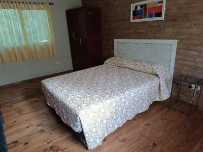 a bed in a bedroom with a wooden floor at Sonidos del Rio Aparts in Santa Rosa de Calamuchita