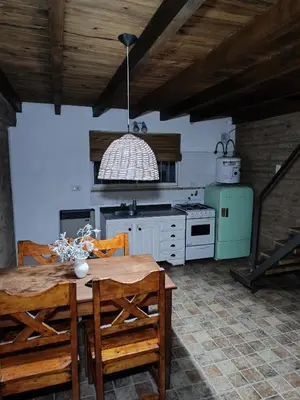 a kitchen with a table and chairs and a stove at Sonidos del Rio Aparts in Santa Rosa de Calamuchita