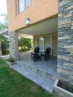 a patio with two chairs and a table in front of a house at Complejo El Aguaribay in Potrero de Garay