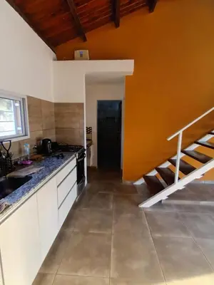 a kitchen with an orange wall and a staircase at Complejo El Aguaribay in Potrero de Garay