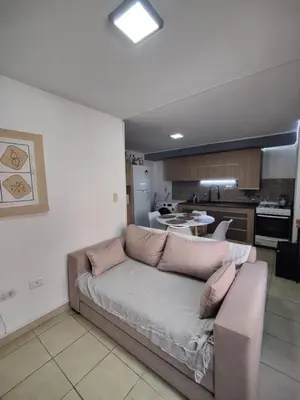 a living room with a couch and a kitchen at Departamento de lujo en Nueva Cordoba in Cordoba