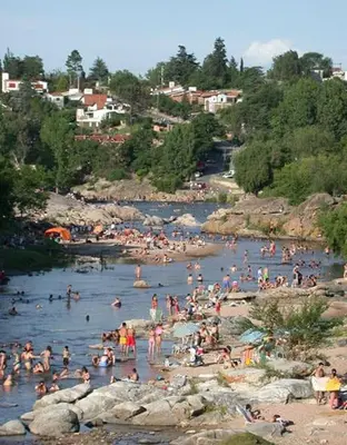 a bunch of people in the water at a beach at Complejo Luluara in Villa Carlos Paz