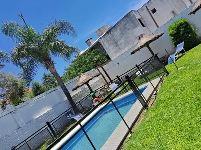 a swimming pool with umbrellas next to a building at Complejo Luluara in Villa Carlos Paz
