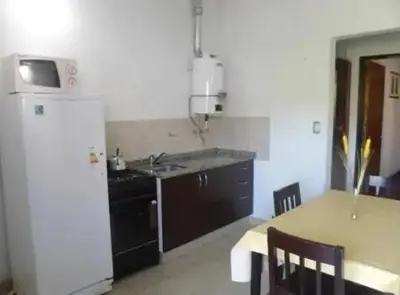 a kitchen with a sink and a refrigerator and a table at Complejo Luluara in Villa Carlos Paz