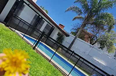 a house with a fence next to a swimming pool at Complejo Luluara in Villa Carlos Paz
