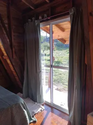 a bedroom with a sliding glass door in a cabin at Sens EcoRefugio in Villa Carlos Paz