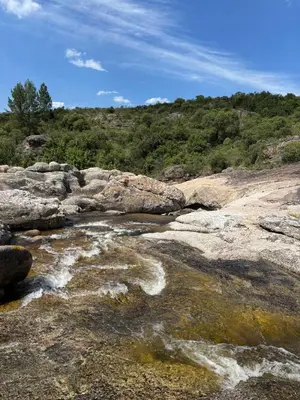 a river with rocks and trees in the background at Sens EcoRefugio in Villa Carlos Paz