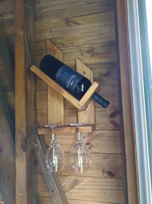 a wine bottle and two glasses on a wooden wall at Sens EcoRefugio in Villa Carlos Paz