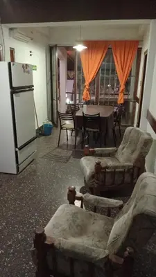 a living room with chairs and a refrigerator and a table at Complejo Luluara in Villa Carlos Paz
