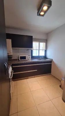 a kitchen with black cabinets and a stove top oven at MAGNUS, 2 baños, 2 hab, TODO NUEVO! en el corazón de Carlos Paz in Villa Carlos Paz