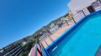 a swimming pool next to a building with a beach at MAGNUS, 2 baños, 2 hab, TODO NUEVO! en el corazón de Carlos Paz in Villa Carlos Paz