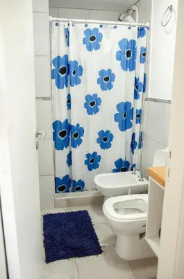 a bathroom with a toilet and a blue shower curtain at Depto 1 dormitorio de categoria en Barrio General Paz in Cordoba
