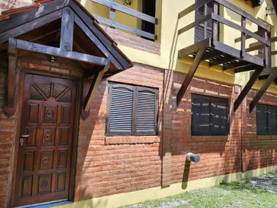a brick building with a wooden door and a balcony at Clima Serrano in Merlo