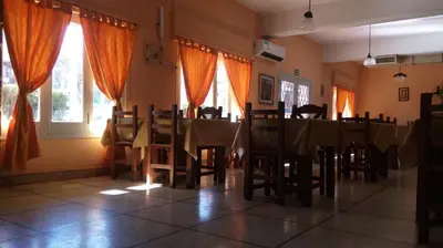 a dining room with a table and chairs and windows at Hotel Nuevo Fatica in Villa Carlos Paz