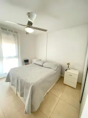 a white bedroom with a bed and a ceiling fan at Espacio C Jardín con estacionamiento in Cordoba