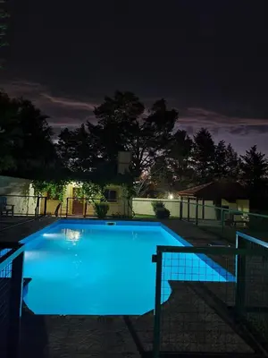 a large blue swimming pool at night at Casa Rivadavia in Mina Clavero