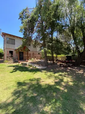 a house with a tree in front of a yard at Cabaña Rubí, Complejo El Colibrí in Villa del Dique