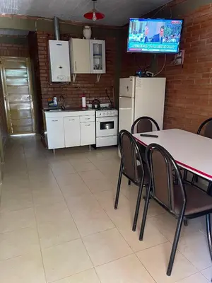 a kitchen with a table and chairs and a tv at Cabañas Mi Ángel in Villa Cura Brochero