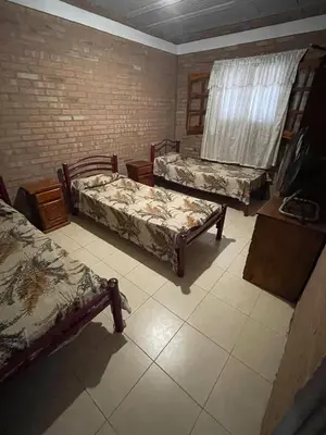 a room with three beds and a brick wall at Cabañas Mi Ángel in Villa Cura Brochero