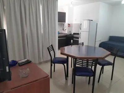a living room with a table and chairs and a kitchen at Abuela Betty in Villa Carlos Paz