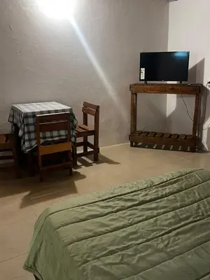 a bedroom with a bed and a table and a tv at Habitaciones Monarcas in Villa Carlos Paz