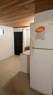 a kitchen with a white refrigerator and a black door at Habitaciones Monarcas in Villa Carlos Paz
