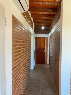 a hallway with a brick wall and a wooden door at El Rincon de las Marias Casa en Planta Alta in San Lorenzo