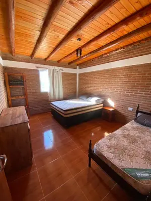 a large room with two beds and a brick wall at El Rincon de las Marias Casa en Planta Alta in San Lorenzo