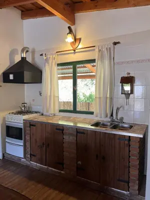a kitchen with a sink and a stove and a window at Cabaña para Grupos en Córdoba Piscina y Asador in Yacanto