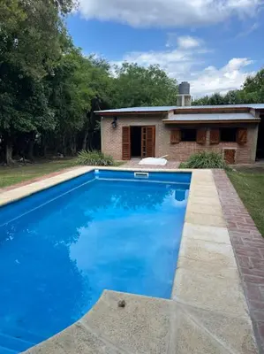 a large blue swimming pool in front of a house at Cabaña para Grupos en Córdoba Piscina y Asador in Yacanto