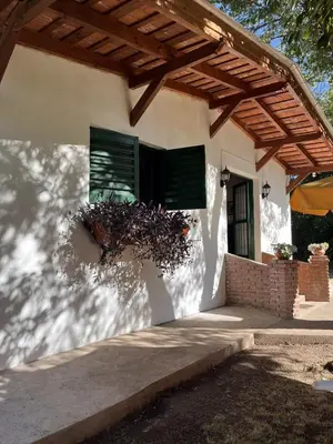 a white house with a wooden roof and a window at Cabaña para Grupos en Córdoba Piscina y Asador in Yacanto