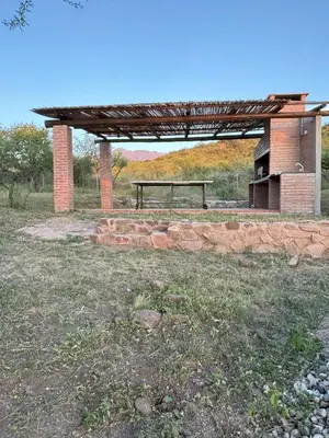 a picnic shelter with a bench in a field at La Fabrica in Yacanto
