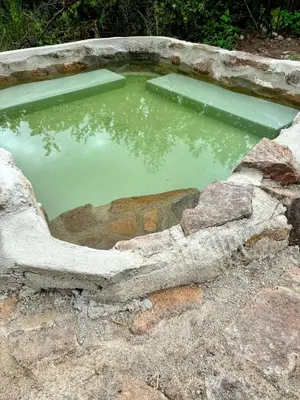 a pool of green water in a stone tub at La Fabrica in Yacanto