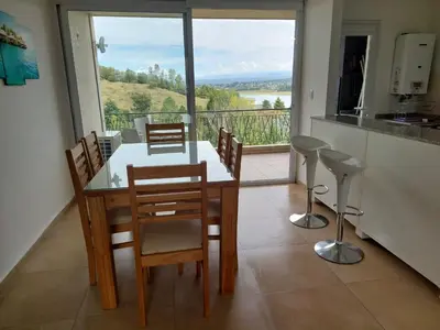 a dining room with a table and chairs and a balcony at Departamento en Potrero de Garay in Potrero de Garay