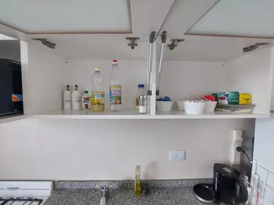 a kitchen with bottles on a shelf above a sink at Departamento en Potrero de Garay in Potrero de Garay