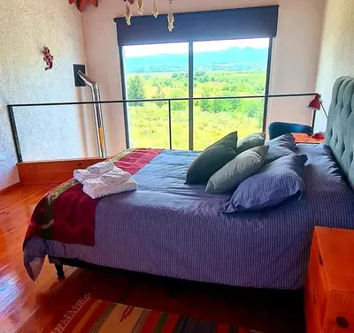 a bedroom with a large bed with a large window at Eco Aldea in Villa Ciudad Parque