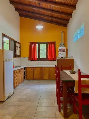 a kitchen with a table and a white refrigerator at CASA del RIO in Villa Ciudad Parque
