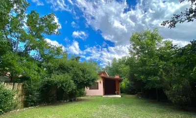 a small house in a yard with trees at CASA del RIO in Villa Ciudad Parque