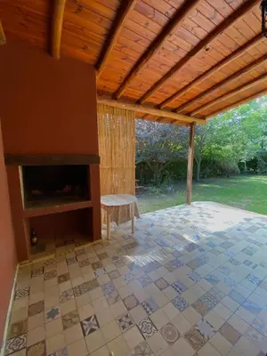 a covered room with a fireplace and a chair at CASA del RIO in Villa Ciudad Parque