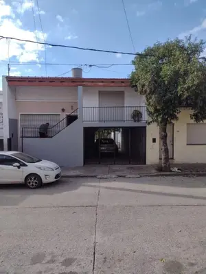 a white house with a car parked in front of it at CASA CENTRICA con SALIDA al RIO in Mina Clavero