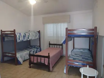 a bedroom with two bunk beds and a table at CASA CENTRICA con SALIDA al RIO in Mina Clavero