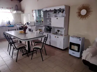 a kitchen with a table and chairs in a room at CASA CENTRICA con SALIDA al RIO in Mina Clavero
