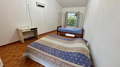 a bedroom with a bed and a table and a window at Gran casa en Villa Del Lago in Villa Carlos Paz