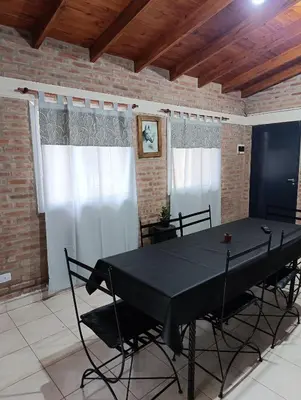 a dining room with a black table and chairs at Complejo La Luisina in Mina Clavero