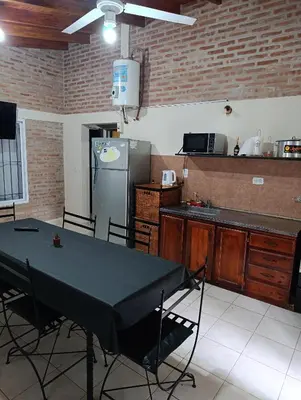 a kitchen with a table and a refrigerator at Complejo La Luisina in Mina Clavero