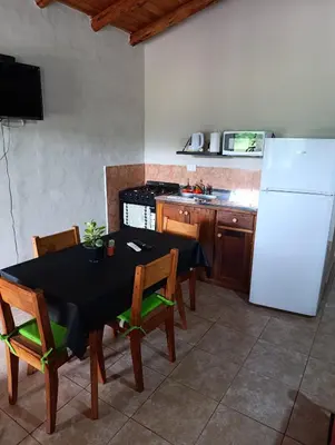 a kitchen with a table with chairs and a refrigerator at Complejo La Luisina in Mina Clavero