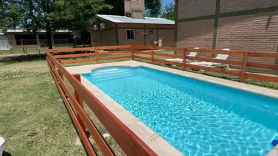 a swimming pool with a wooden fence around it at Complejo La Luisina in Mina Clavero