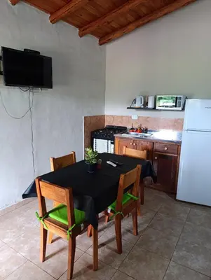a kitchen with a table with chairs and a refrigerator at Complejo La Luisina in Mina Clavero