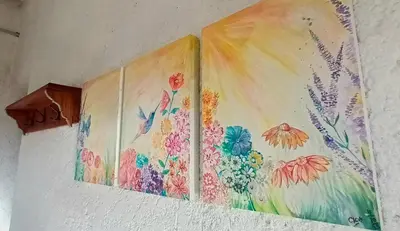 three paintings of flowers on a wall at La calendula eco cabaña in Los Hornillos